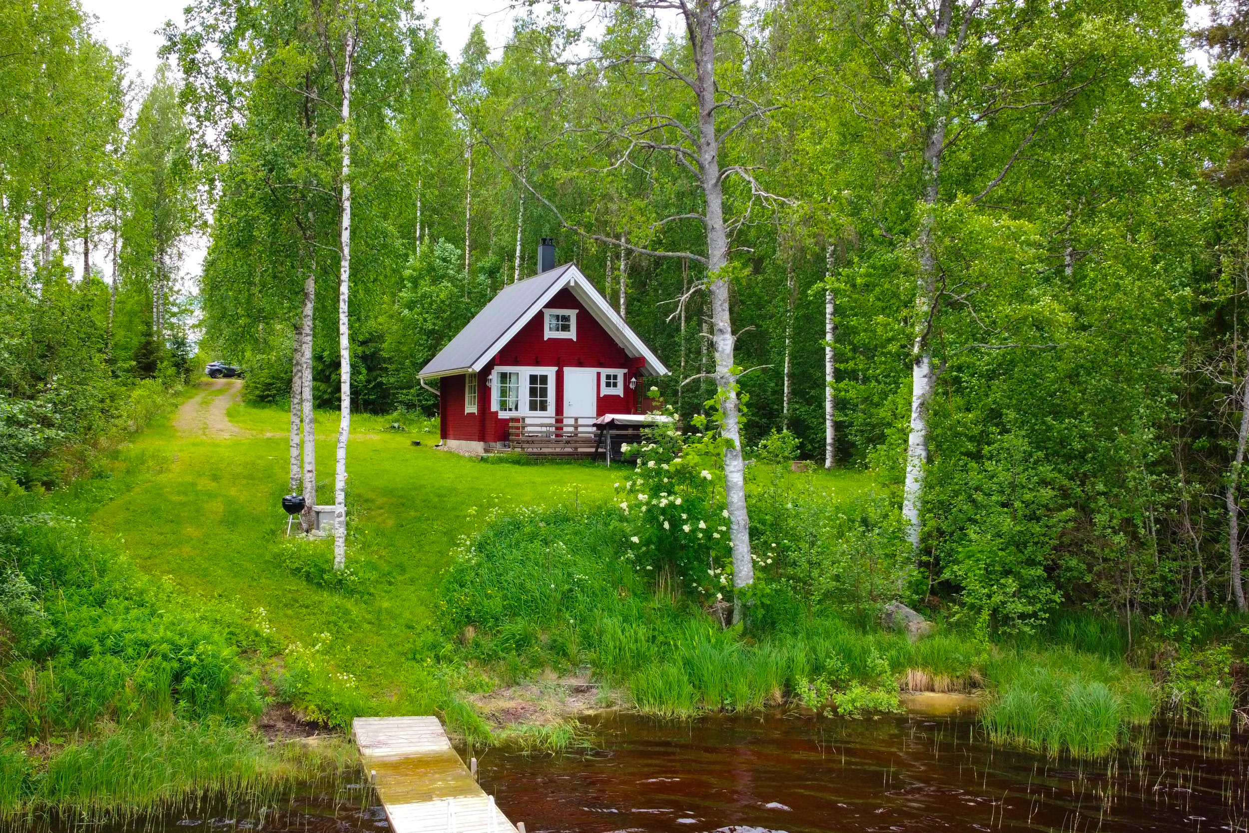 Punainen hirsimökki järven rannassa